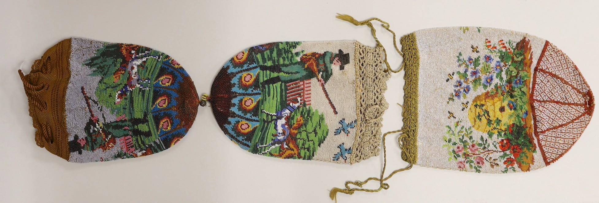 Two 19th century draw string beaded bags with hunting scenes, possibly American and a similar beaded bag depicting a bee hive in a garden.